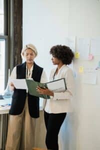 Deux femmes professionnelles examinant des documents dans un bureau moderne.